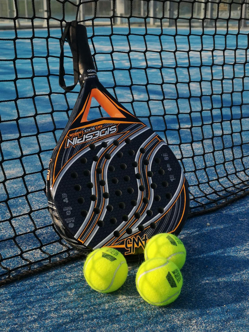 Padel ketsjer og bolde på bane i sollys